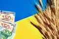 Sheaf of ripe wheat on national Ukrainian flag with USA dollars and EU Euro banknotes