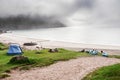 Sheep sleep on a sandy beach close to tourist tents