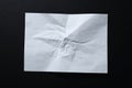 A sheet of crumpled white paper on a black background.Crumpled white paper background. Wrinkled sheet texture, top view. Royalty Free Stock Photo