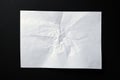 A sheet of crumpled white paper on a black background.Crumpled white paper background. Wrinkled sheet texture, top view. Royalty Free Stock Photo