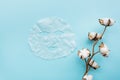 Sheet facial mask and cotton flower on pastel blue paper background. Skin care, dermatology, beauty concept. Top view, flat lay,