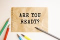 A sheet of kraft paper torn from a notebook lies on the table. Text on ARE YOU READY sheet. Colored pens and a pencil. Royalty Free Stock Photo