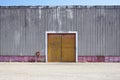 The sheet metal factory wall with the entrance door in the industrial park.The red door of the factory building.