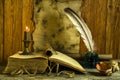 A sheet of old paper with space for text, an open book and a burning candle, an inkwell with a feather on a wooden background Royalty Free Stock Photo