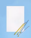 Sheet of paper with blue and yellow striped pencils on pastel blue background