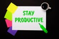 A sheet of paper with the inscription STAY PRODUCTIVE, a cup of coffee, bright multi-colored stickers for notes and a green marker Royalty Free Stock Photo