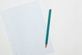 a sheet of paper for notes and a green pencil, white background Royalty Free Stock Photo