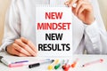 A sheet of paper with text NEW MINDSET NEW RESULTS, multicolored markers on a white table. Business and educational concept Royalty Free Stock Photo