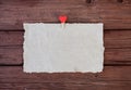 A sheet of parchment paper with a clothespin with a red heart on a wooden background. Royalty Free Stock Photo