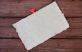 A sheet of parchment paper with a clothespin with a red heart on a wooden background. Royalty Free Stock Photo