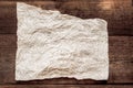 Sheet of parchment on a wooden background. Crumpled sheet of parchment paper as background, texture. Royalty Free Stock Photo