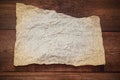 Sheet of parchment on a wooden background. Crumpled sheet of parchment paper as background, texture. Royalty Free Stock Photo