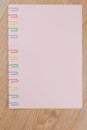 A sheet of pink paper fixed with multi-colored paper clips on the oak plank table close, the Board of the table is located