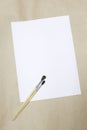 Sheet of white paper and artistic brushes on a crafting background