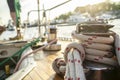 Sheet winch on the wooden deck of the yacht on a blurred background of the pier with boats, the sea and sunlight.