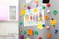 Sheets of paper, child`s drawing and magnets on refrigerator door in kitchen Royalty Free Stock Photo