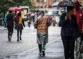 Enjoy the weather coat worn by high street shopper walking in depressing dark wet gloomy town centre. Umbrellas. Royalty Free Stock Photo