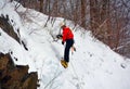 Solo ice climber swinging ice tool ascending huge ice wall