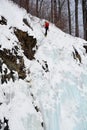 Solo ice climber swinging ice tool ascending huge ice wall