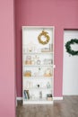 Shelf with Christmas decor in a pink colored living room and hallway