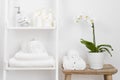 Shelf with clean towels, candles, flowerpot on bathroom wooden table