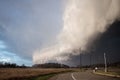 A shelf cloud and severe thunderstorm approaches rapidly with a road and streetlights in the foreground. Royalty Free Stock Photo
