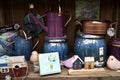 A shelf with colorful garden ornaments for sale, bright blue plant pots, watering cans and a sign.