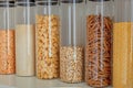 Shelf in the kitchen with stocks of cereals and pasta: oatmeal, peas, rice, pasta in glass jars. Order in the kitchen