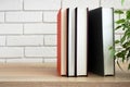 Vertical standing group of books on modern shelf in front of white wall