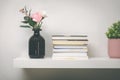 Shelf on white wall with books and flower pots Royalty Free Stock Photo