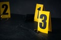 Shell casings and evidence marker on black slate table, closeup. Crime scene