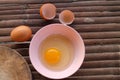 shell with egg and open Eggs in a pink bowl Placed near to the butcher on Bamboo battens.Top view closeup