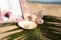 Shell with gold rings, wedding invitation and beautiful flower on sandy beach Royalty Free Stock Photo
