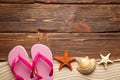 Shell, starfish, sand and flip flops on wooden board