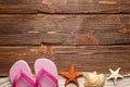 Shell, starfish, sand and flip flops on wooden board