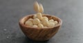 Shelled macadamia nuts falling into olive wood bowl on terrazzo surface Royalty Free Stock Photo