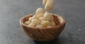 Shelled macadamia nuts falling into olive wood bowl on terrazzo surface Royalty Free Stock Photo