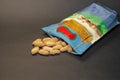 Shelled peanuts falling out of the packaging on a grey background Royalty Free Stock Photo