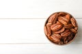 Shelled pecan nuts in bowl and space for text on wooden background Royalty Free Stock Photo