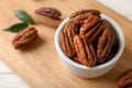 Shelled pecan nuts in bowl on wooden board. Royalty Free Stock Photo