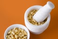 Shelled pine nuts in bowl and mortar over orange Royalty Free Stock Photo