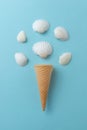 Shellfish ice cream concept on blue surface. Ice cream cone with white shells