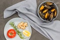 Shellfish mussels in shells in gray bowl. Rosemary, lemon and ginger in gray plate. Gray napkin