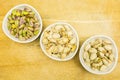 Shelling pistachio nuts. Whole, nutshell and peeled pistachios in bowls. View from above.