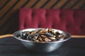 Shells clams with parsley in copper cooking dish on dark wooden table with blurred restaurant background.