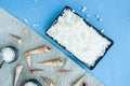 Shells, sea salt in a black rectangular dish, small bowls Asian style and fabric burlap on blue background