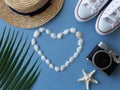 Shells, a sea ster, sneakers, a tropical leaf, a summer hat and camera