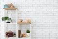 Shelves with books, burning candles, seashells and other decorations near white brick wall Royalty Free Stock Photo
