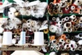 Shelves with rolls of colored fabrics and spools of sewing thread on the foreground