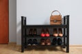 Shelving unit with shoes and stylish bag near grey wall in hallway Royalty Free Stock Photo